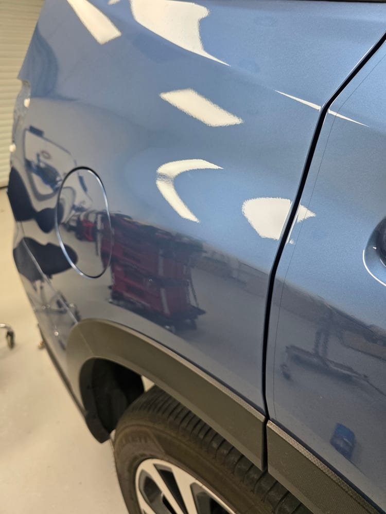 The same rear quarter panel after repair, smooth with no dent near the fuel door