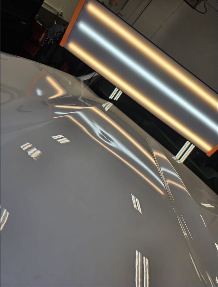 Dented hood before repair, light board reflection visibly kinked