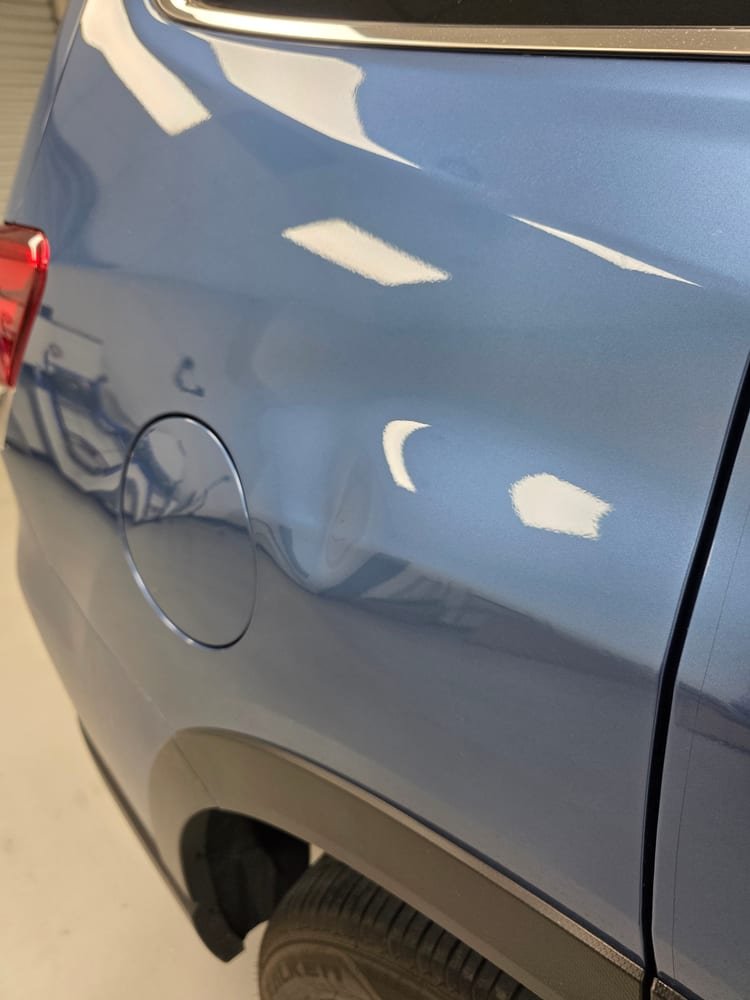 Dented rear quarter panel before repair, next to the fuel door